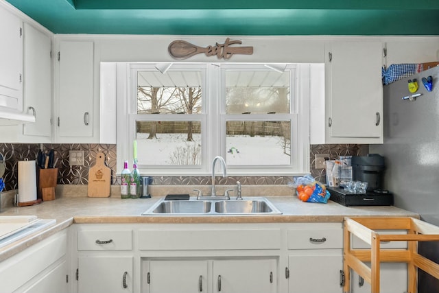 kitchen with tasteful backsplash, white cabinetry, and sink