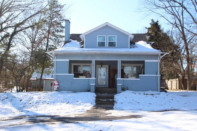 bungalow-style home with covered porch, a chimney, and fence