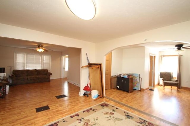 interior space featuring visible vents, arched walkways, a ceiling fan, and wood finished floors