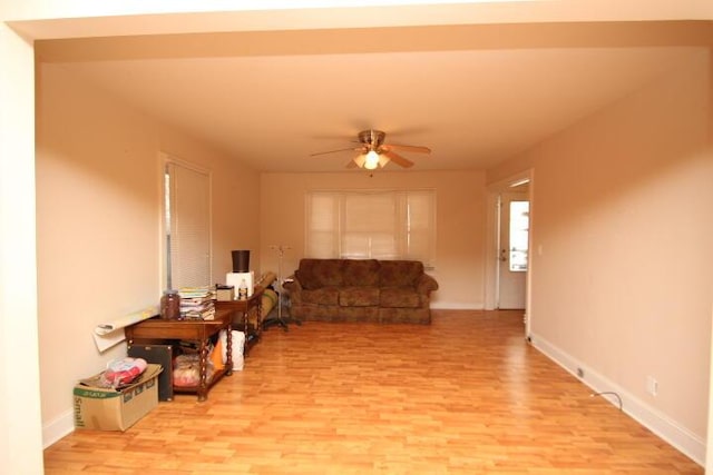 living area featuring light wood-style floors, ceiling fan, and baseboards