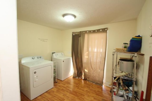 laundry room with light wood-style floors, washing machine and dryer, laundry area, and a textured ceiling