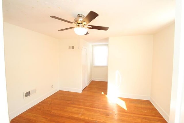 empty room featuring wood finished floors, visible vents, and baseboards