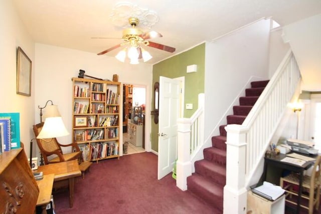 sitting room featuring ceiling fan, stairs, and carpet flooring