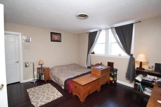 bedroom with visible vents, baseboards, and wood finished floors