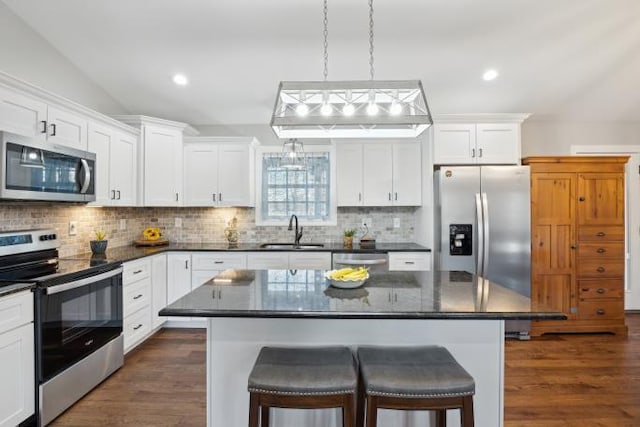 kitchen featuring stainless steel appliances, a sink, dark wood-style floors, tasteful backsplash, and a kitchen bar