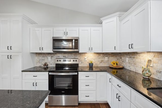 kitchen featuring stainless steel appliances, backsplash, white cabinetry, vaulted ceiling, and dark stone counters