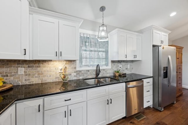 kitchen with stainless steel appliances, white cabinets, a sink, and decorative backsplash