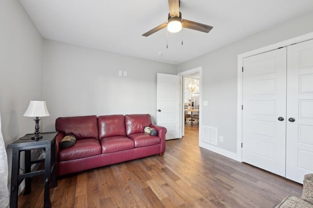 living area with visible vents, ceiling fan, baseboards, and wood finished floors