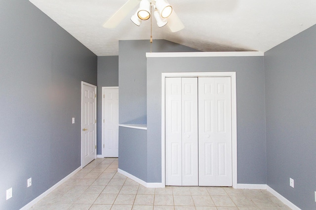 unfurnished bedroom with ceiling fan, vaulted ceiling, a closet, and light tile patterned floors