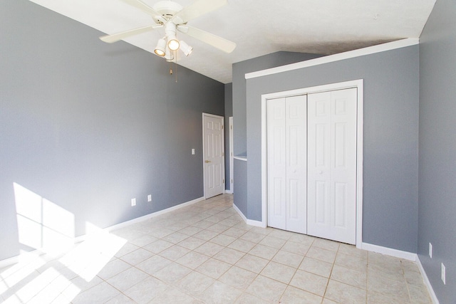 unfurnished bedroom with light tile patterned floors, vaulted ceiling, a closet, and ceiling fan