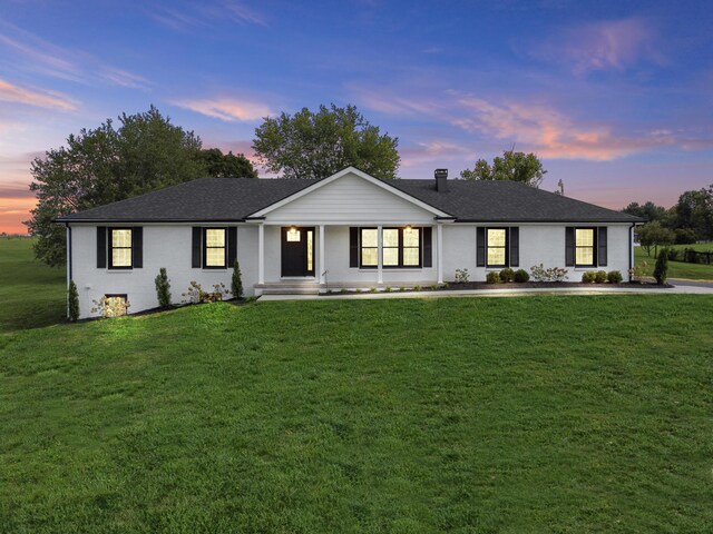 ranch-style home with a porch and a lawn