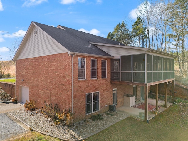 rear view of property with a garage, a patio area, and a sunroom