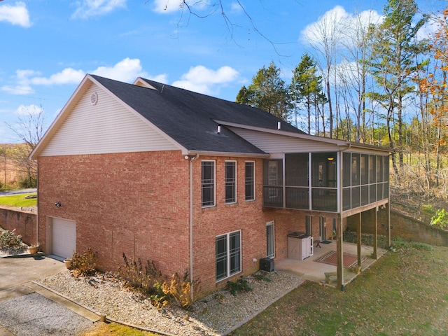 back of property featuring a garage, a sunroom, central AC unit, and a patio