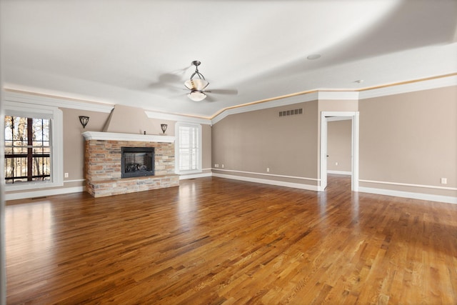 unfurnished living room with a stone fireplace, hardwood / wood-style flooring, ceiling fan, and plenty of natural light