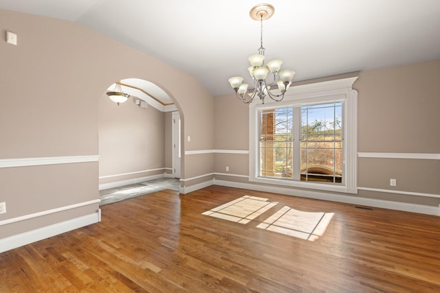 unfurnished dining area featuring wood-type flooring, an inviting chandelier, and lofted ceiling