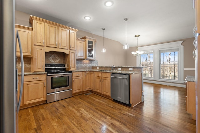 kitchen featuring appliances with stainless steel finishes, decorative light fixtures, decorative backsplash, sink, and light stone counters