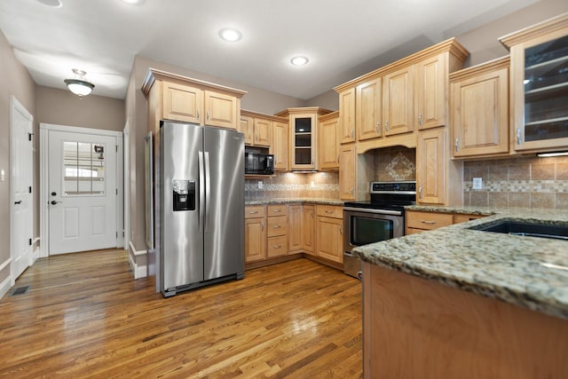 kitchen with wood-type flooring, light brown cabinets, appliances with stainless steel finishes, backsplash, and light stone countertops