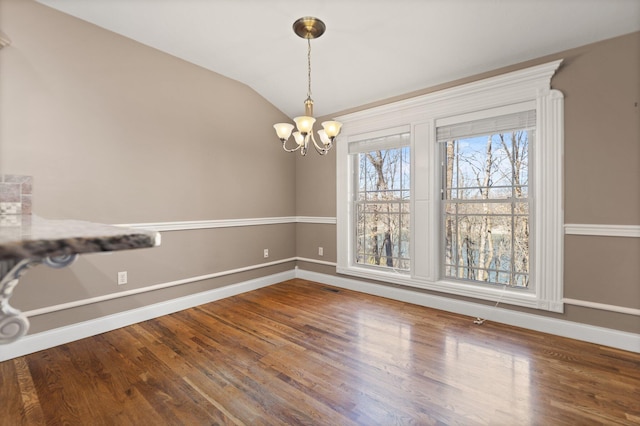 unfurnished dining area featuring wood-type flooring, lofted ceiling, and a chandelier