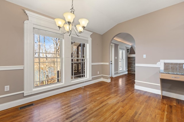 unfurnished dining area featuring wood-type flooring, a notable chandelier, and lofted ceiling