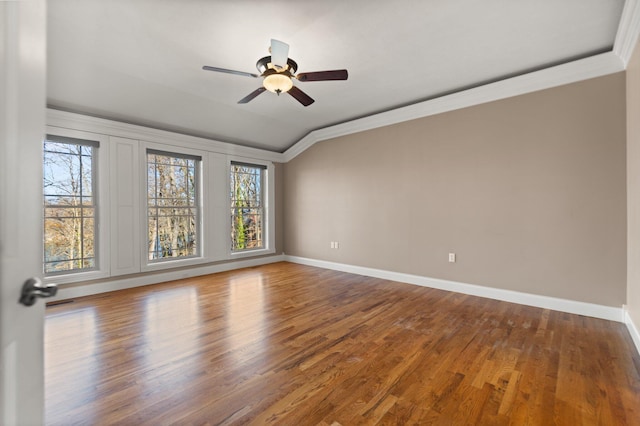 empty room with vaulted ceiling, a wealth of natural light, crown molding, and wood-type flooring