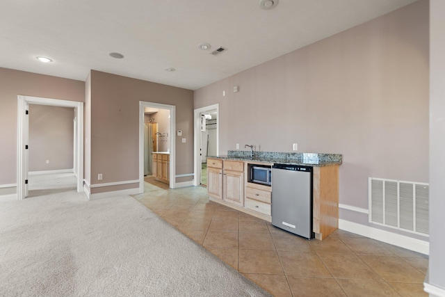 kitchen featuring dishwasher, sink, light brown cabinetry, and light tile patterned floors