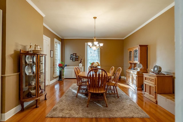 dining area with light hardwood / wood-style flooring, an inviting chandelier, and crown molding