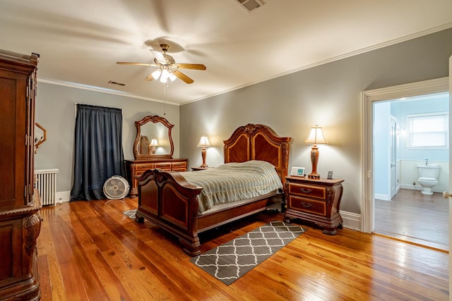 bedroom featuring radiator, ensuite bath, wood-type flooring, ornamental molding, and ceiling fan