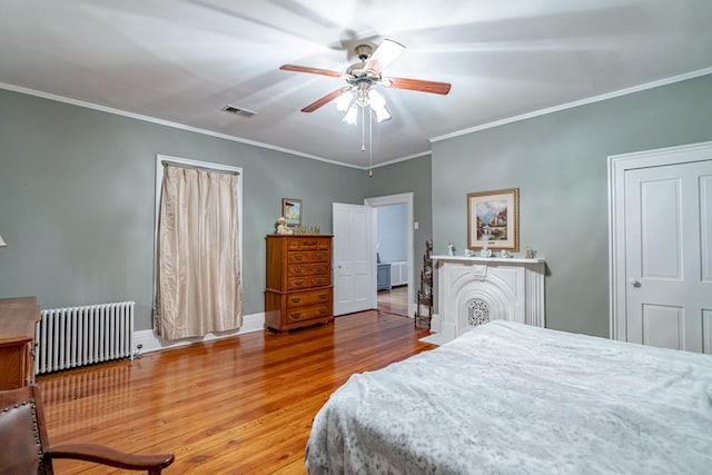 bedroom featuring ceiling fan, wood-type flooring, radiator heating unit, and crown molding