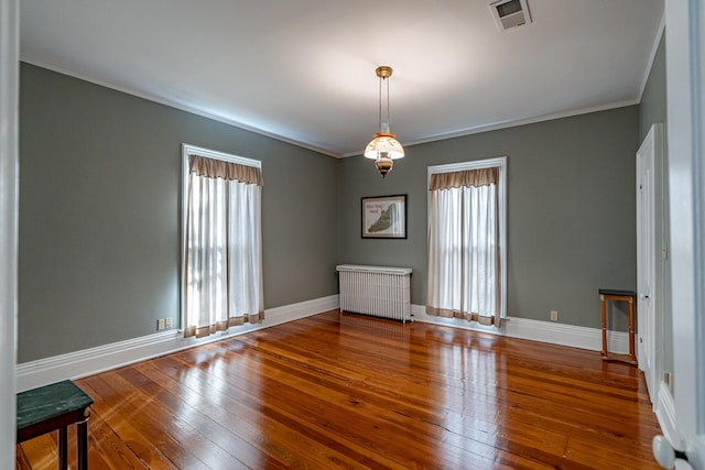 spare room with wood-type flooring, a wealth of natural light, radiator, and crown molding