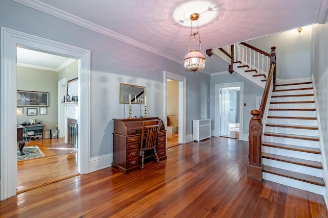 entrance foyer with hardwood / wood-style flooring, a chandelier, radiator heating unit, and ornamental molding