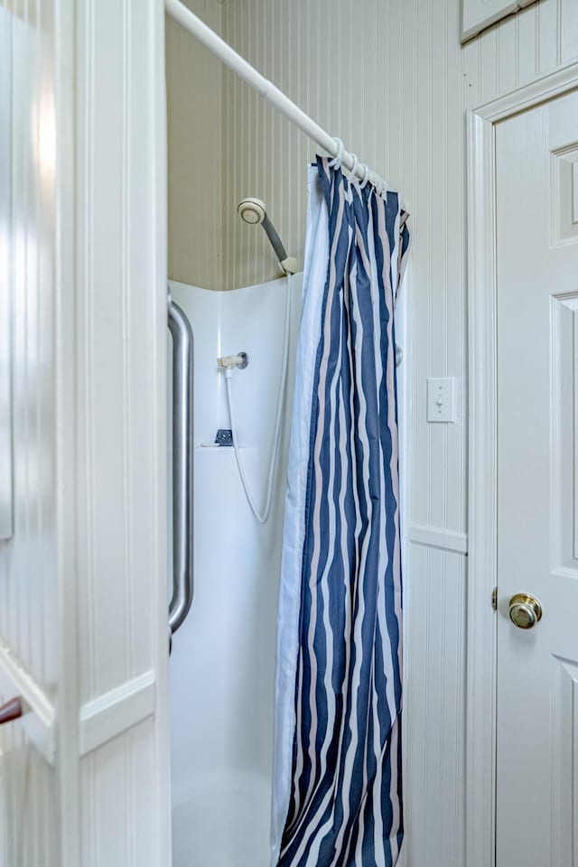 bathroom with a shower with curtain and wooden walls