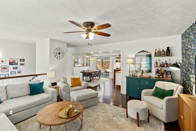 living room featuring ceiling fan, a textured ceiling, and light wood-type flooring