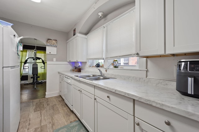 kitchen featuring light stone counters, white appliances, sink, and white cabinets