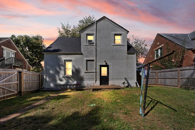 back house at dusk with a lawn