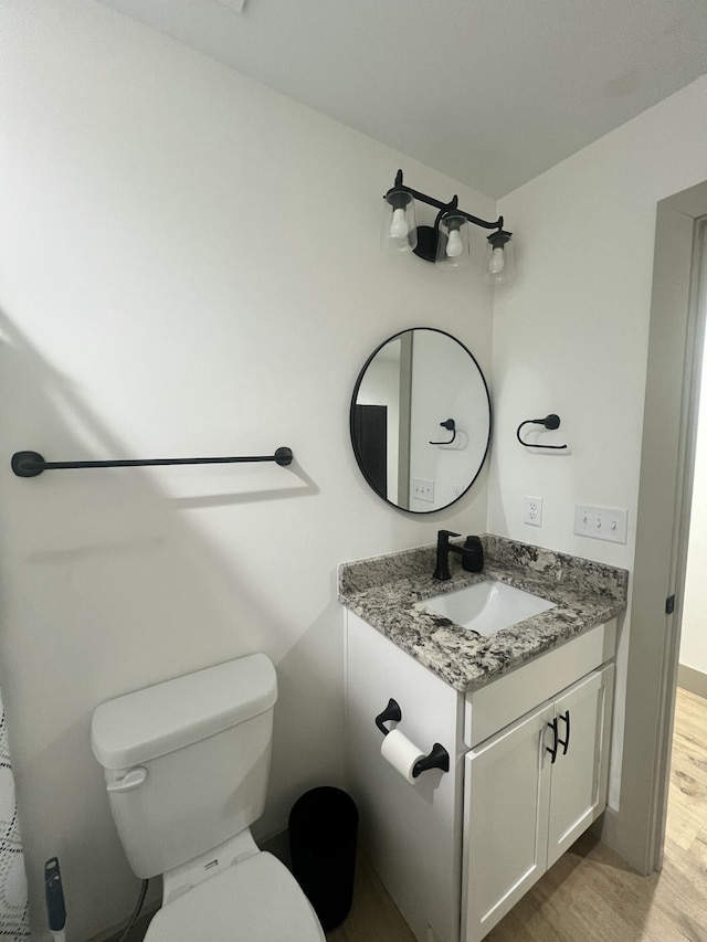 bathroom with hardwood / wood-style flooring, vanity, and toilet