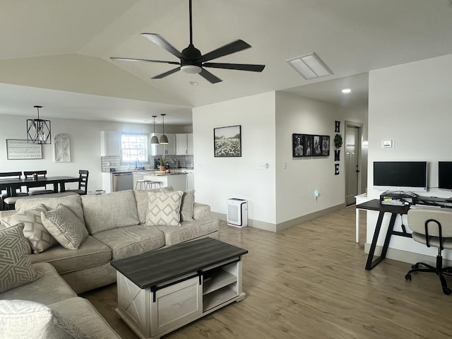 living room with sink, vaulted ceiling, light hardwood / wood-style floors, and ceiling fan