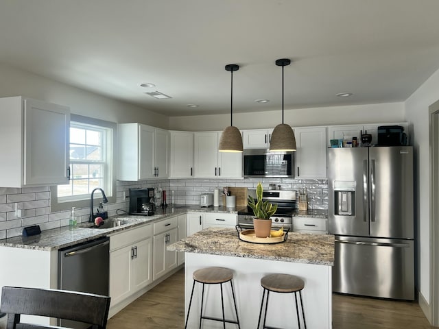 kitchen featuring appliances with stainless steel finishes, pendant lighting, sink, white cabinets, and a center island