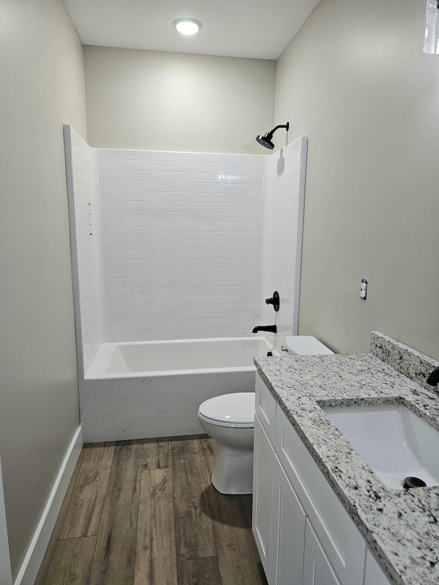 bathroom featuring baseboards, toilet, wood finished floors, tub / shower combination, and vanity