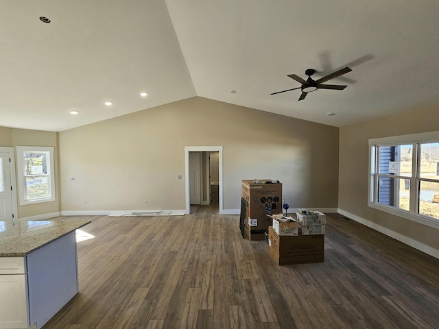 unfurnished living room featuring dark wood-style floors, vaulted ceiling, plenty of natural light, and baseboards