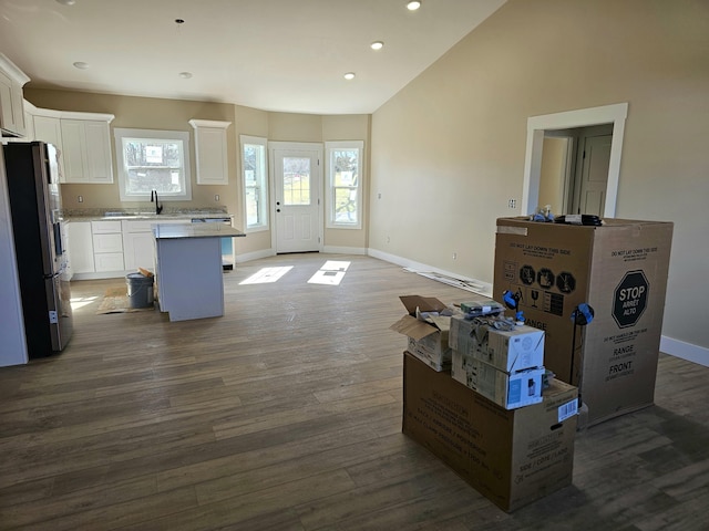 kitchen featuring dark wood-type flooring, freestanding refrigerator, vaulted ceiling, a kitchen island, and baseboards