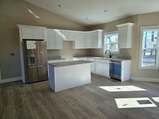 kitchen featuring lofted ceiling, a sink, appliances with stainless steel finishes, a center island, and dark wood-style floors