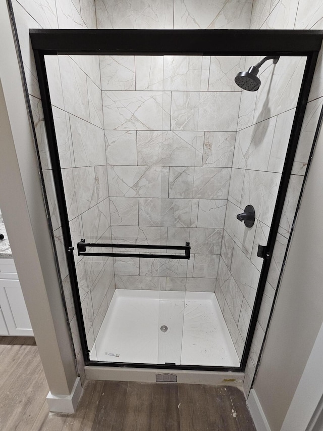 full bath featuring a stall shower, wood finished floors, and baseboards