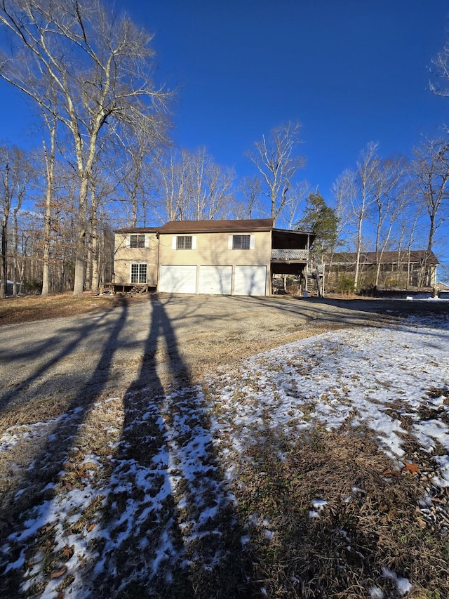 snow covered rear of property featuring a carport and a garage