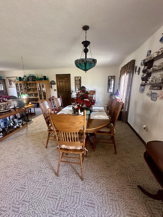 carpeted dining room featuring a textured ceiling