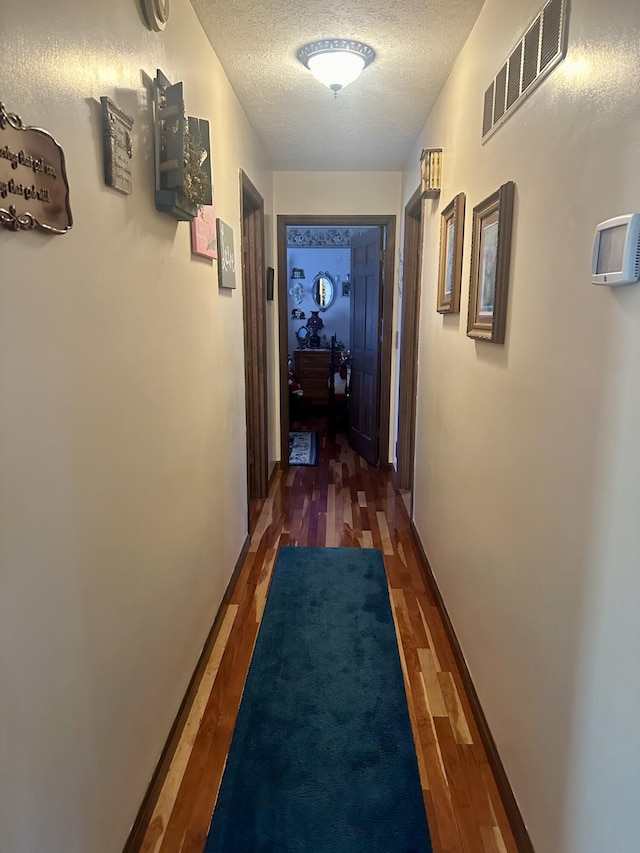 corridor featuring dark hardwood / wood-style floors and a textured ceiling