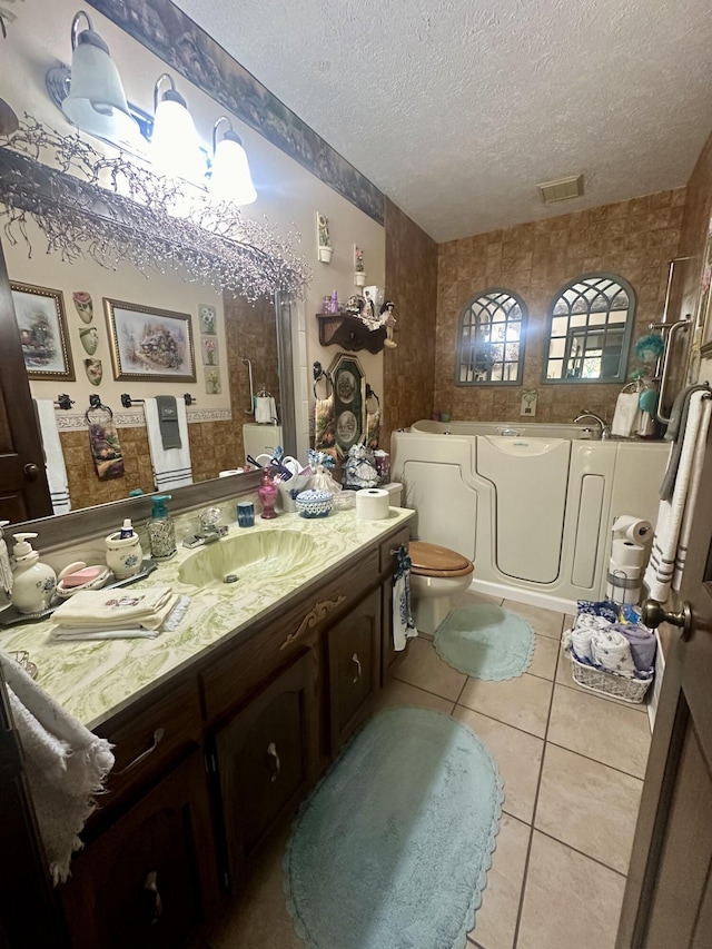 bathroom featuring tile patterned flooring, a bathtub, vanity, a textured ceiling, and toilet