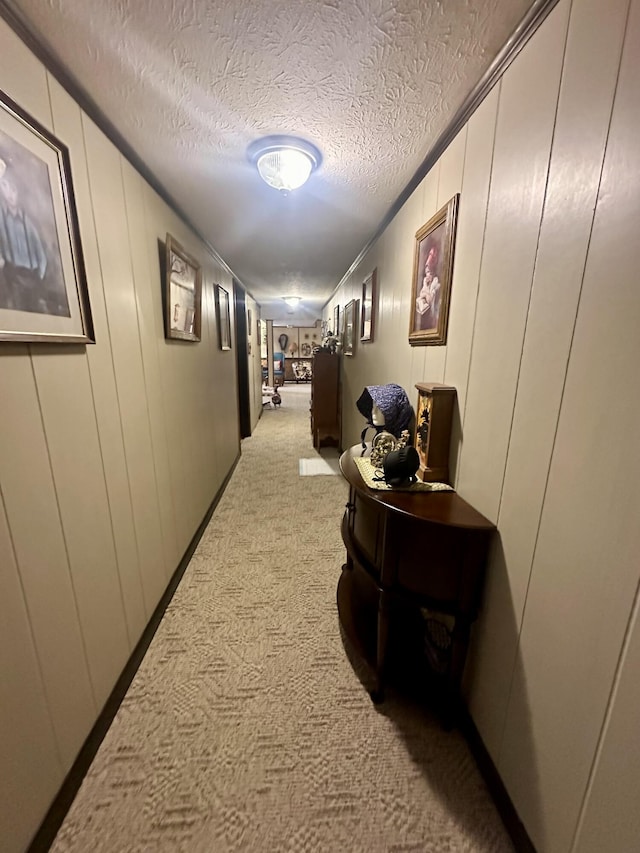 corridor with light colored carpet and a textured ceiling