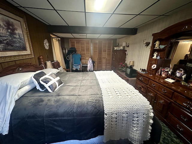 bedroom with a drop ceiling and wood walls