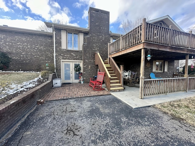 back of property featuring french doors, a wooden deck, and a patio