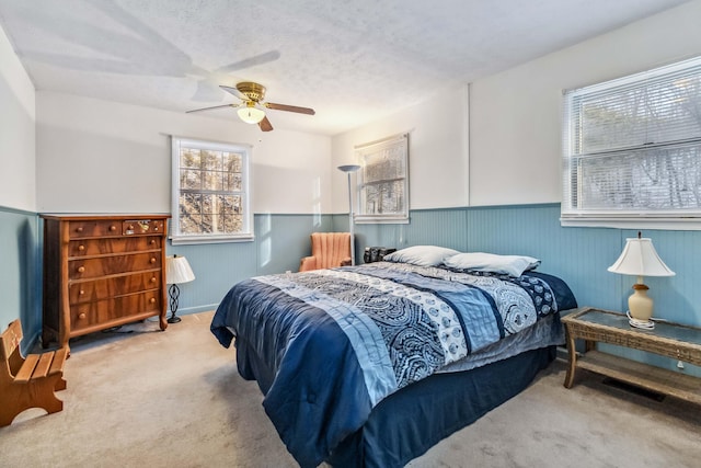 carpeted bedroom with ceiling fan and a textured ceiling